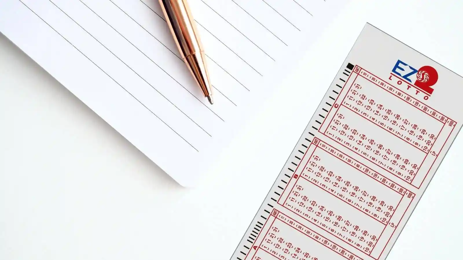 white notebook with lines, gold pen and 2D pcso lotto ticket
