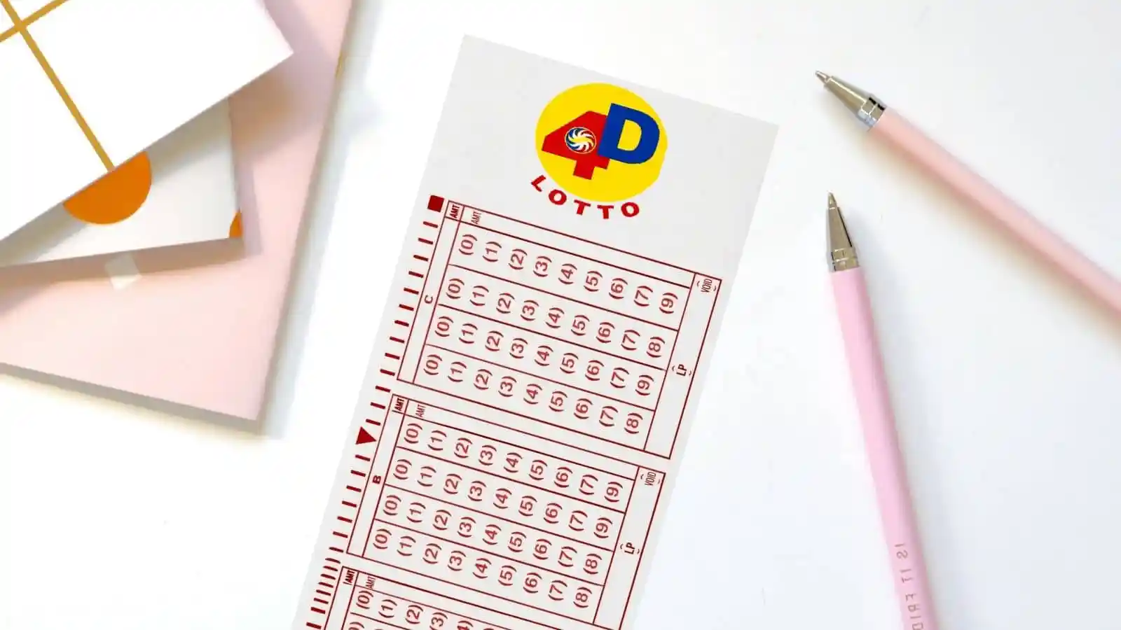 paper notebooks, pcso 4D ticket and pink pens on white desk
