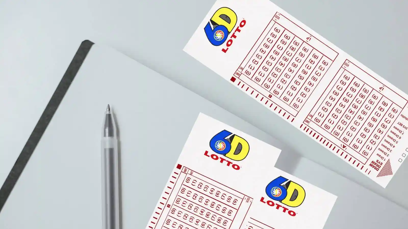 open notebook, pen and 6D pcso lotto ticket on gray surface